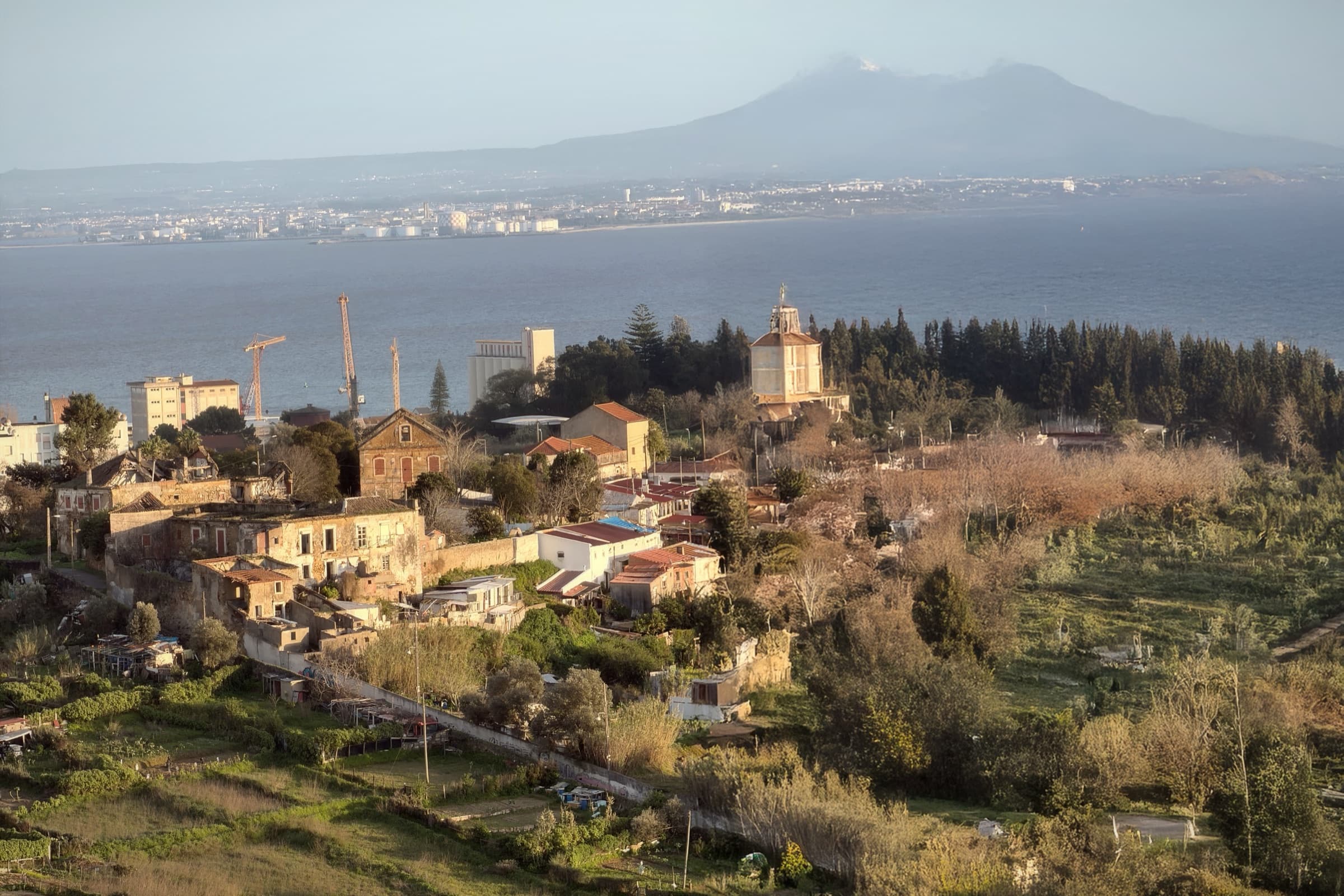A wide landscape of river, hills, rooftops, and pale winter light.